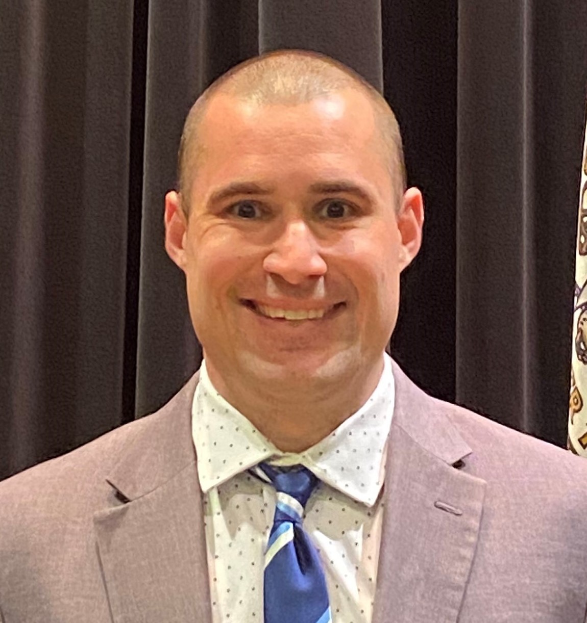 a smiling man wearing a suit and tie