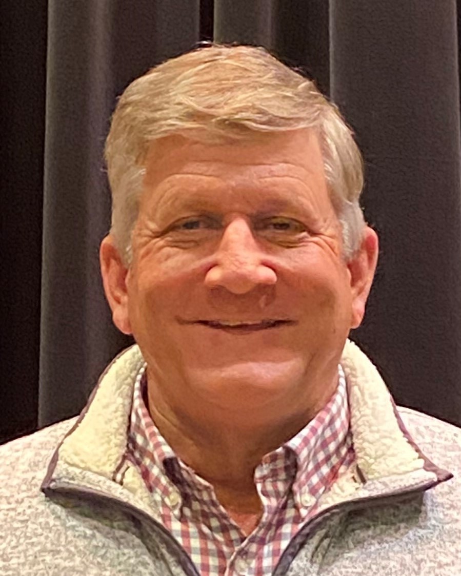 a smiling man with gray hair wearing a light colored sweater