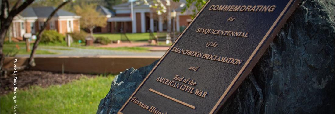 stone with plaque commemorating the emanicpation proclamation. Dogwood blossoms and blue sky in the background.