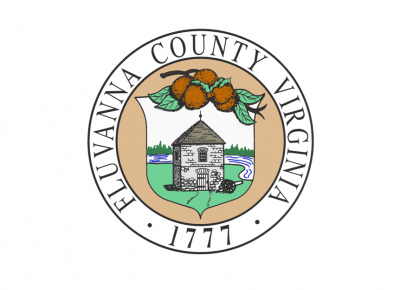 The Fluvanna County official seal depicting a small stone building surrounded by grass and a river. 